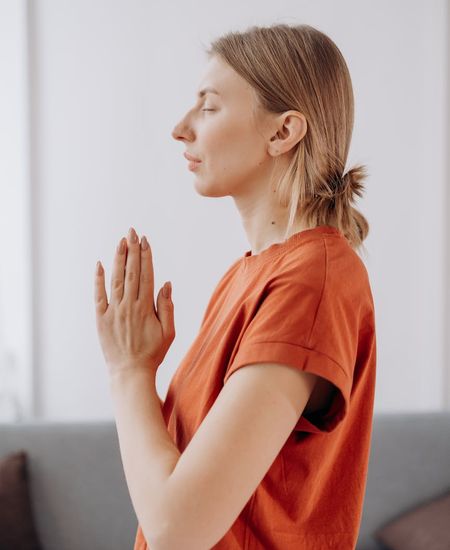 Woman practicing a calm yoga pose in a sand-toned room.